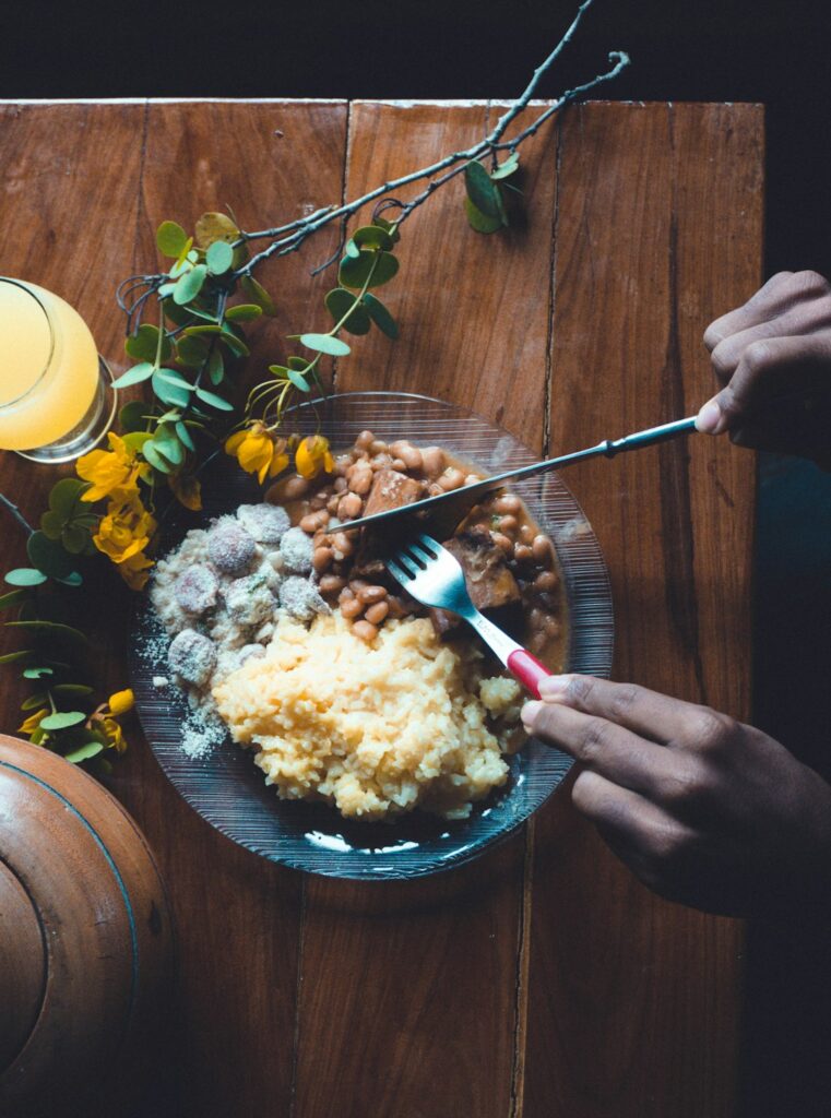A person eating soft mashed food from a bowl beside a glass of water during dental implant recovery.
